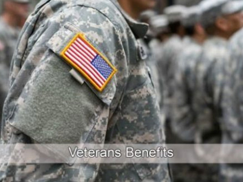 Close-up of a person in military uniform with a U.S. flag patch, standing among others in uniform. Text overlay reads "Veterans Benefits.